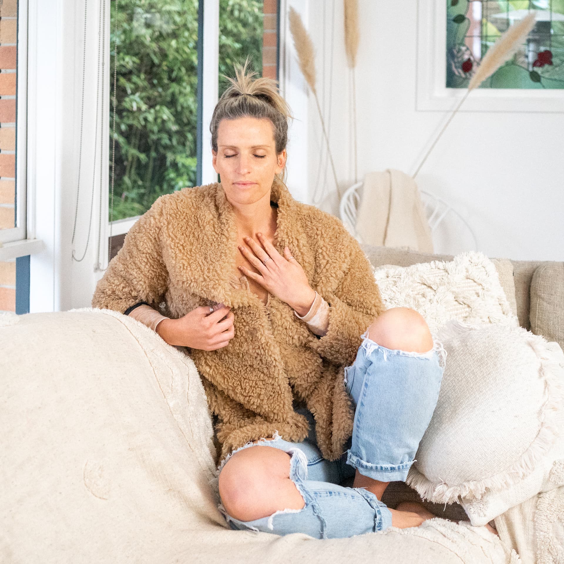 Jacintha Field sitting quietly on a couch with a hand over her heart